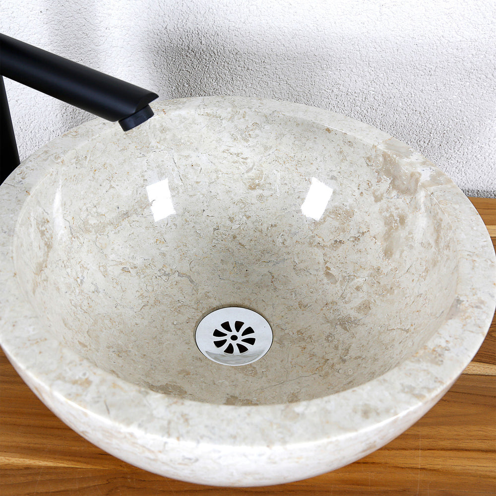 Detailed view of a round countertop washbasin made of light natural stone with a polished inner surface and central drain