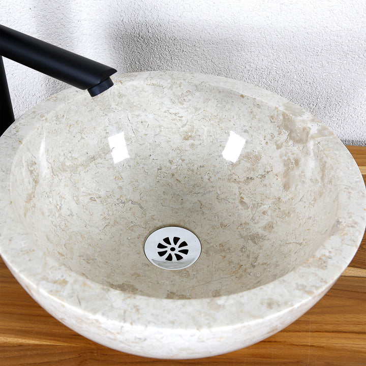 Detailed view of a round countertop washbasin made of light natural stone with a polished inner surface and central drain