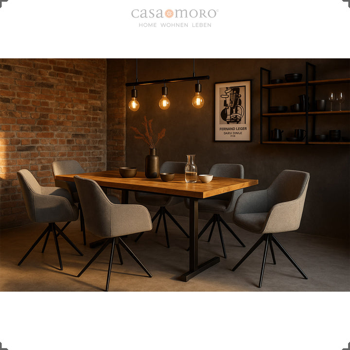 Six 360° swivel gray upholstered chairs with armrests at a wooden table in a modern dining room with a brick wall and atmospheric lighting