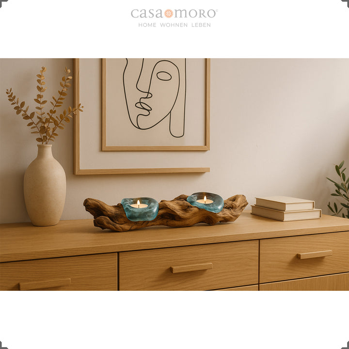 Elongated tea light holder made of glass and burl wood on a sideboard, its soft light complements the natural, modern living room design.