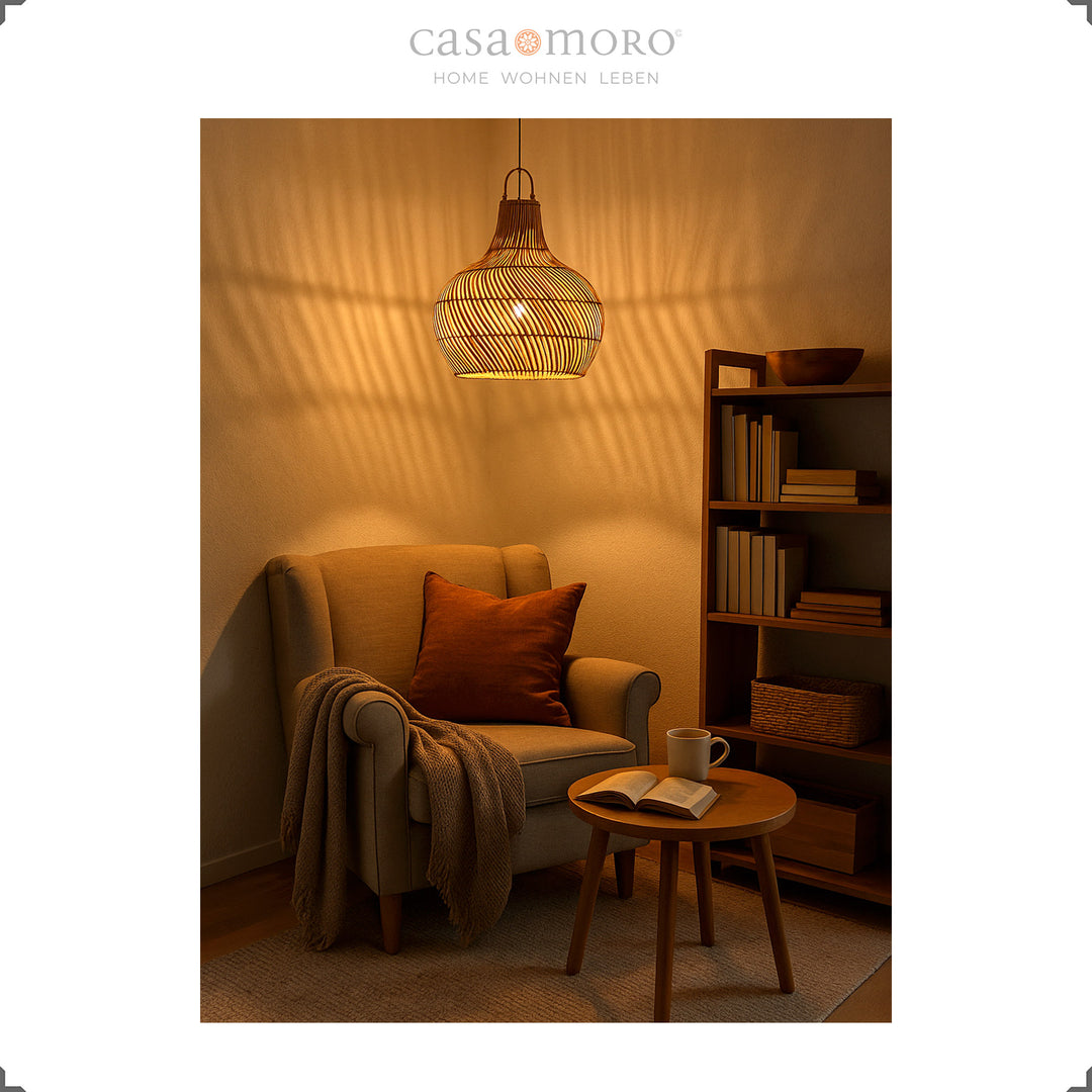 Hanging rattan lamp with warm light above a reading chair creates an atmospheric shadow play on the wall