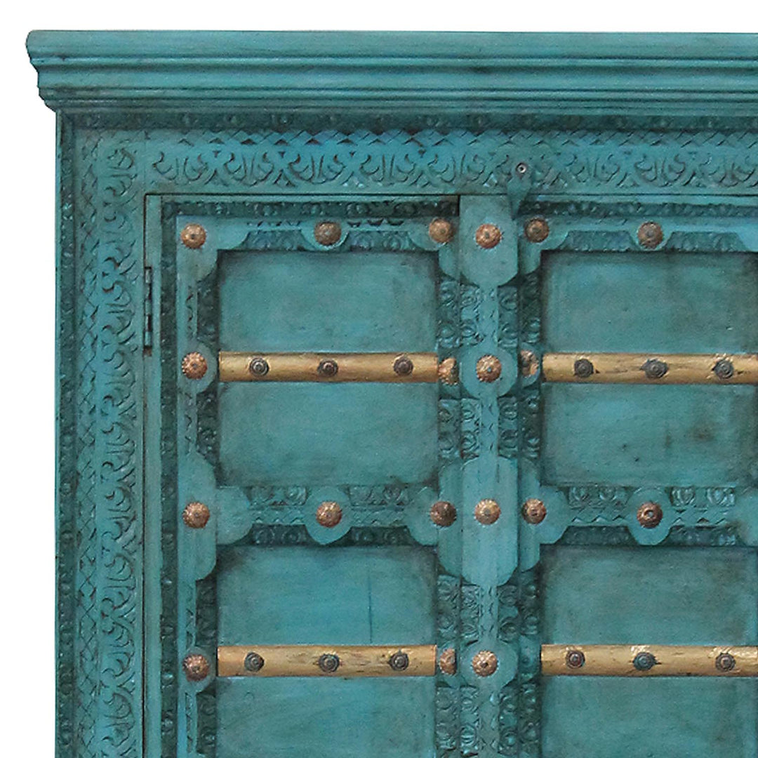 Close-up of turquoise carved ornaments, gold-coloured crosspieces and decorative fittings on the cabinet doors.
