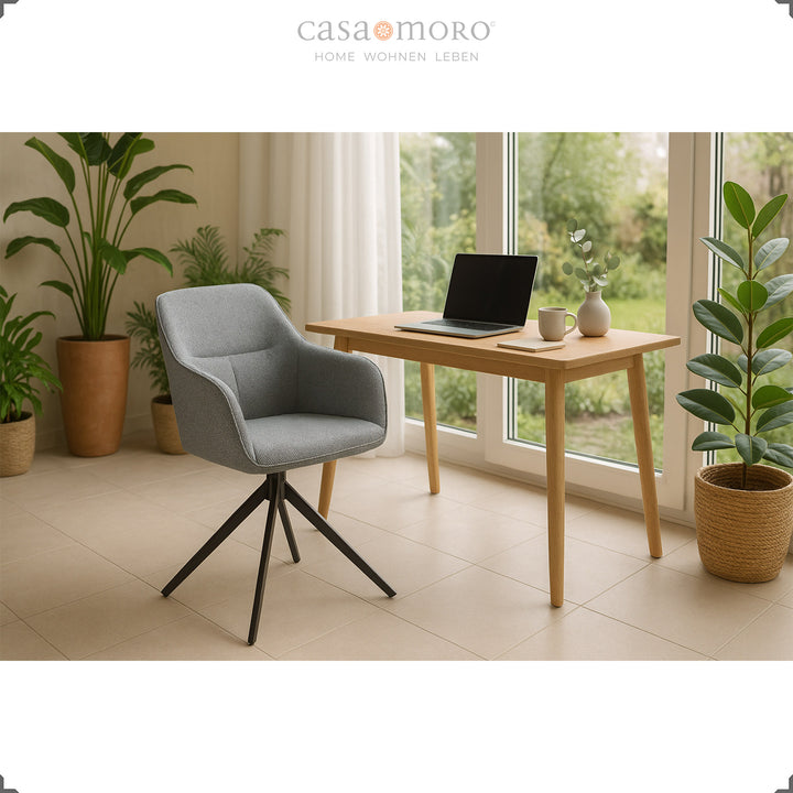 360° rotating upholstered chair with armrests in gray at a wooden table with a laptop, framed by plants and large windows in a bright living environment