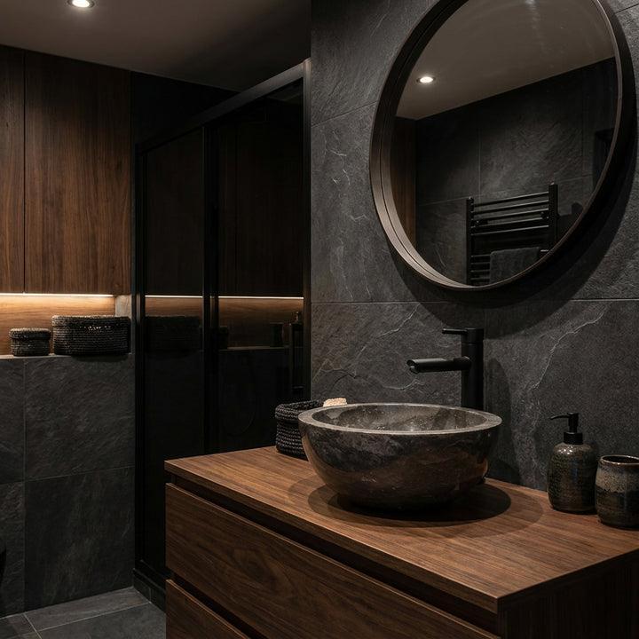Round natural stoneWashbasin as an attachment on a dark wooden washbasin with a black fitting in an elegant, dark bathroom ambience
