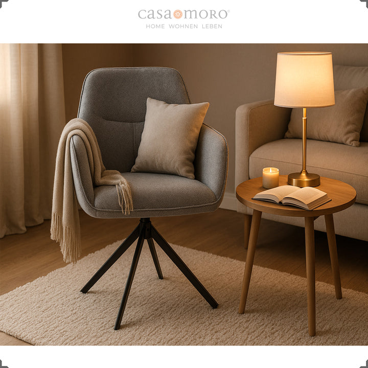 360° rotating upholstered chair with armrests in gray, comfortably arranged next to a side table, lamp and sofa in a modern living room 