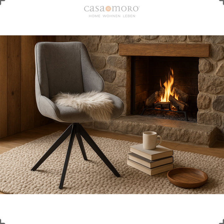 360° rotating dining room chair in gray in front of a fireplace with fur cushion, stack of books and cup - cozy living scene with warm light