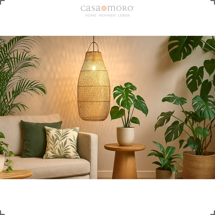 Large rattan ceiling lamp above sofa in living room with lots of green plants and warm light