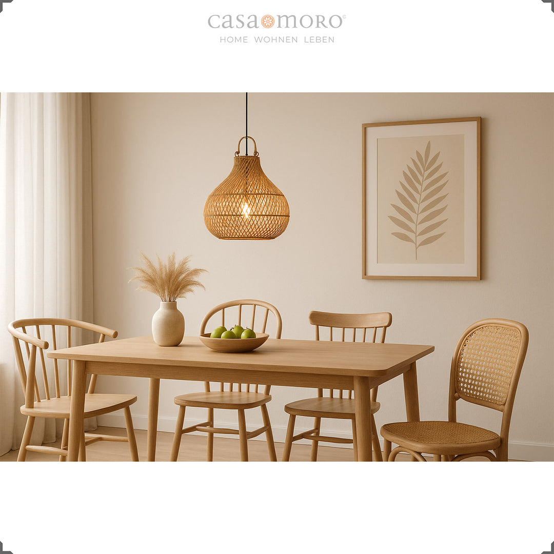 Hanging rattan lamp above dining table in bright dining room with natural decoration and warm light