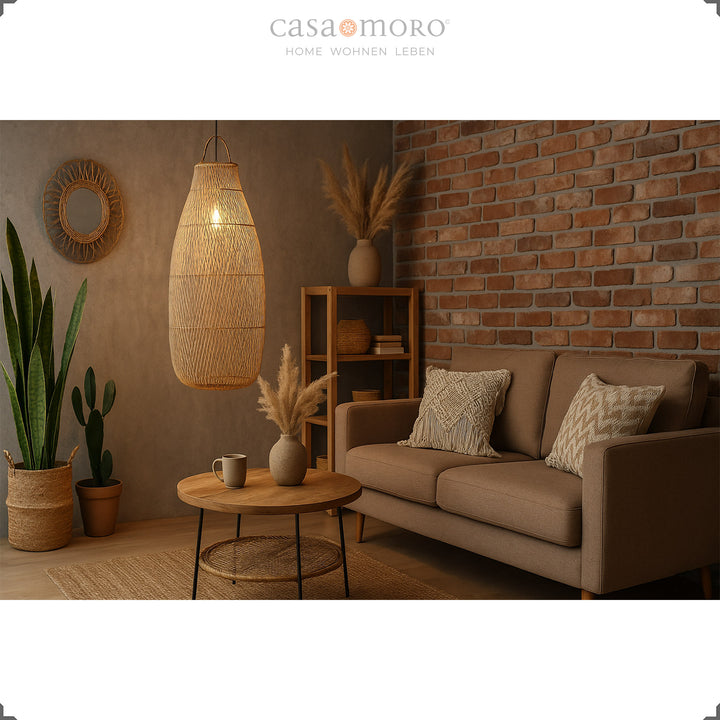 Tall, hanging rattan lamp in the living room with a brick wall and warm play of light