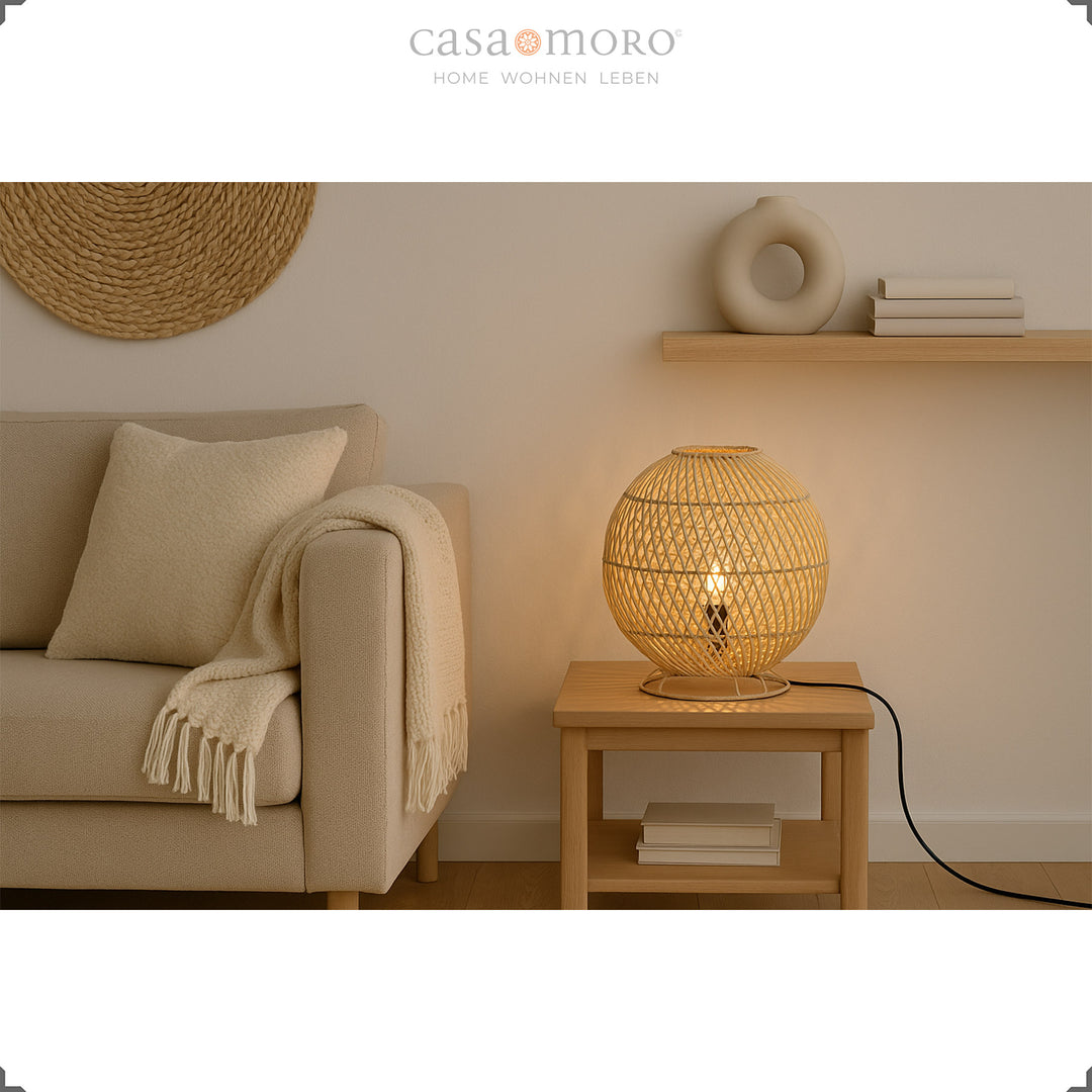 Round rattan table lamp on side table next to sofa, warm light and natural furnishings