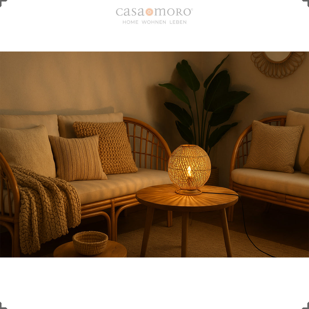 Round rattan lamp on coffee table between seating furniture, warm light and cozy ambience