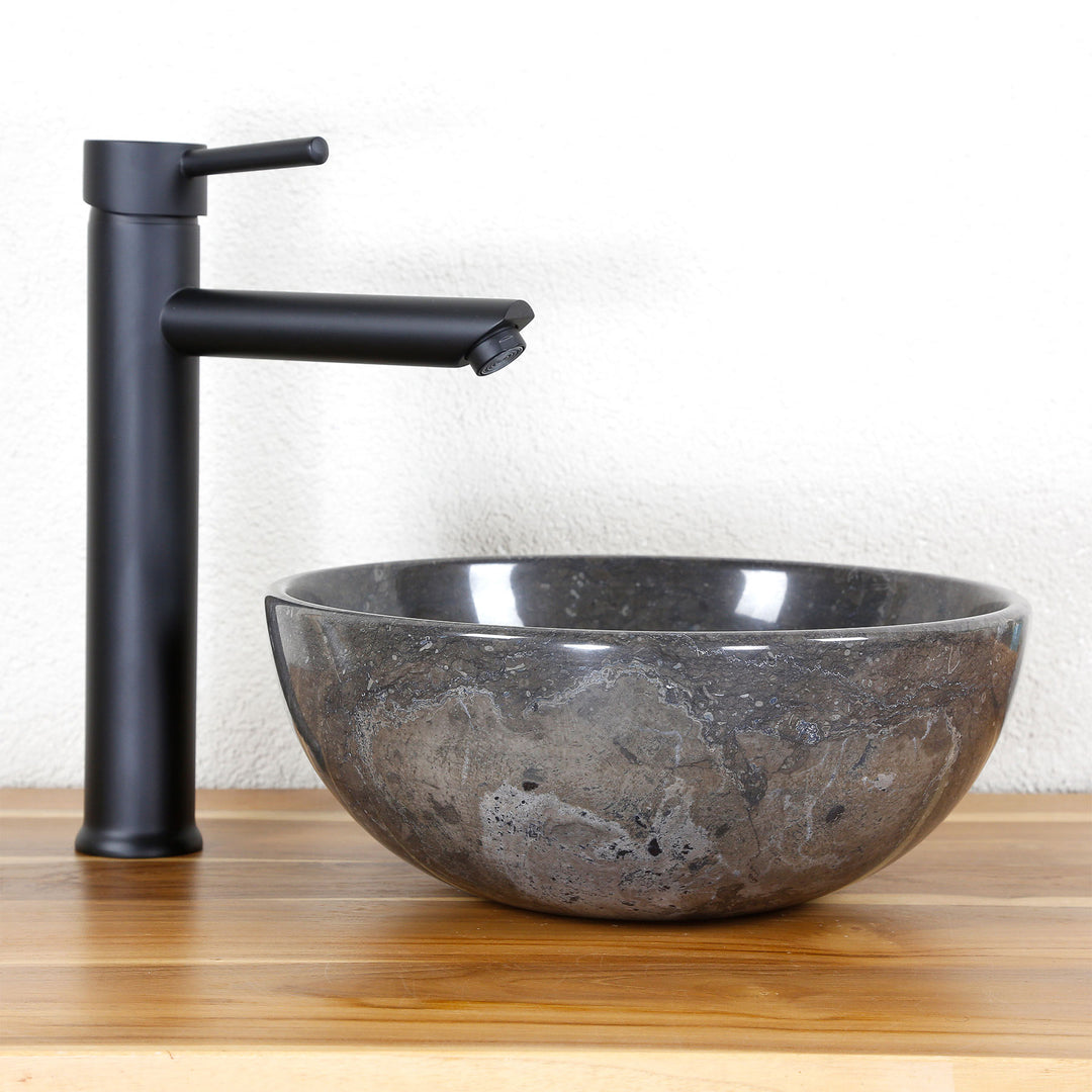 Round Washbasin Made of natural stone with dark grain on a wooden top, combined with a black stand-alone fitting
