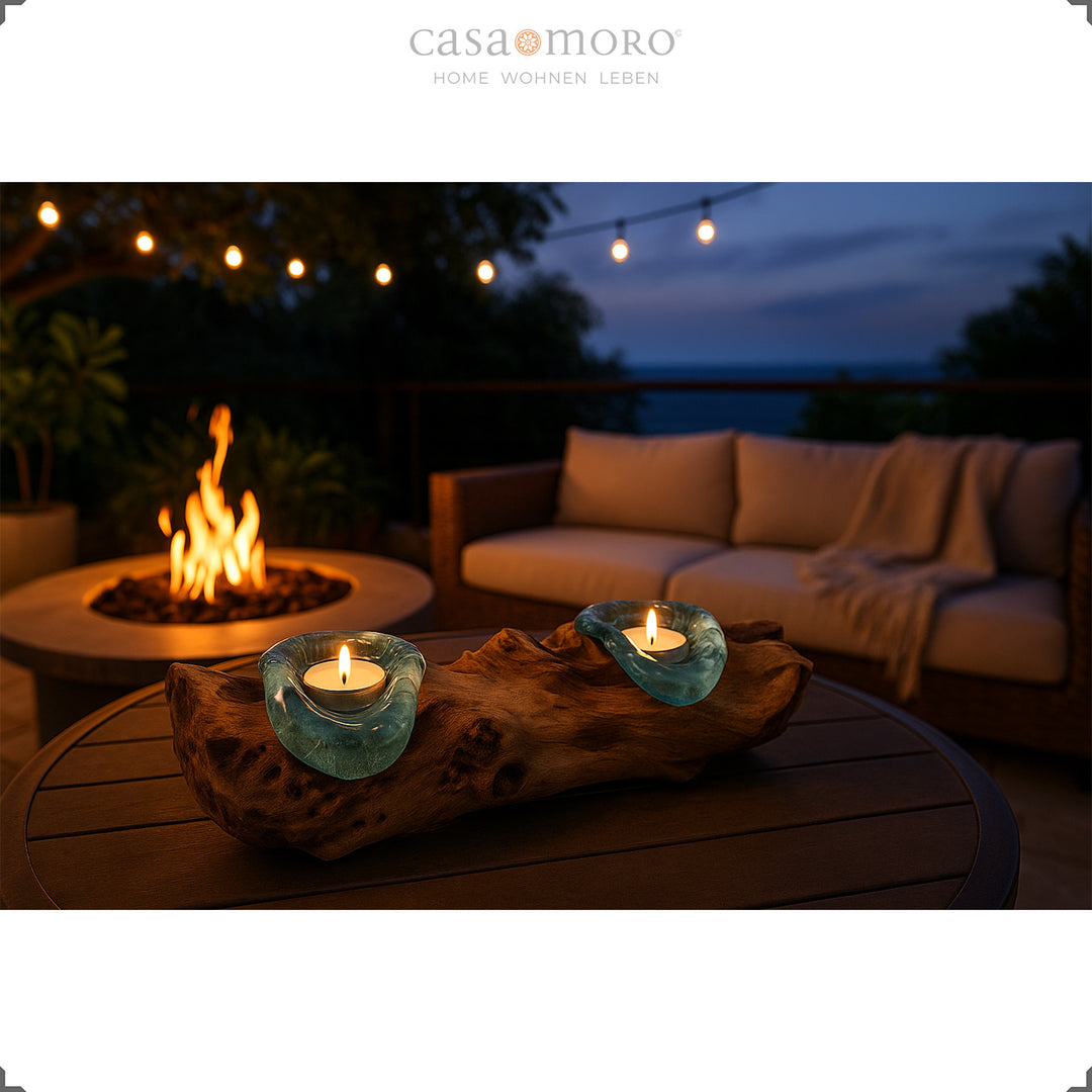 2 tea light holders made of glass and root wood on an outdoor table, its warm light complements the cozy evening atmosphere on the terrace.