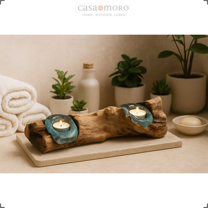 2 tea light holders made of glass and burl wood in the bathroom, its soft light complements the relaxed spa atmosphere with plants and towels.
