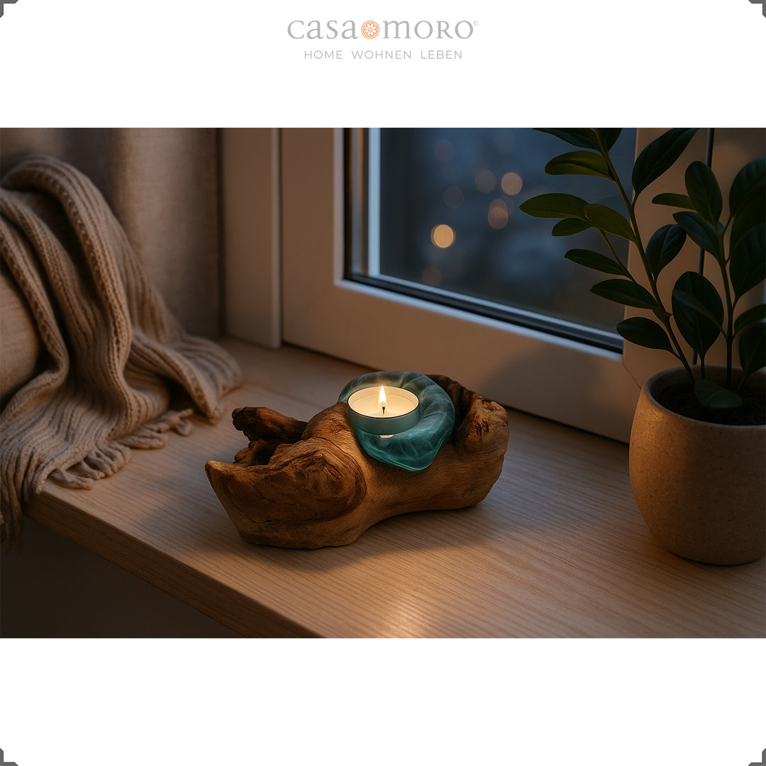 Tea light holder made of glass and root wood on a windowsill, its soft light creates a calm, soothing atmosphere in the evening.