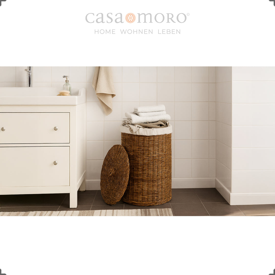 Brown rattan laundry basket with lid and cotton insert in the bathroom, decoratively filled with towels