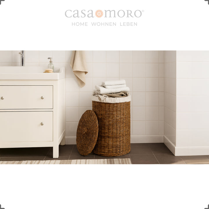 Brown rattan laundry basket with lid and cotton insert in the bathroom, decoratively filled with towels