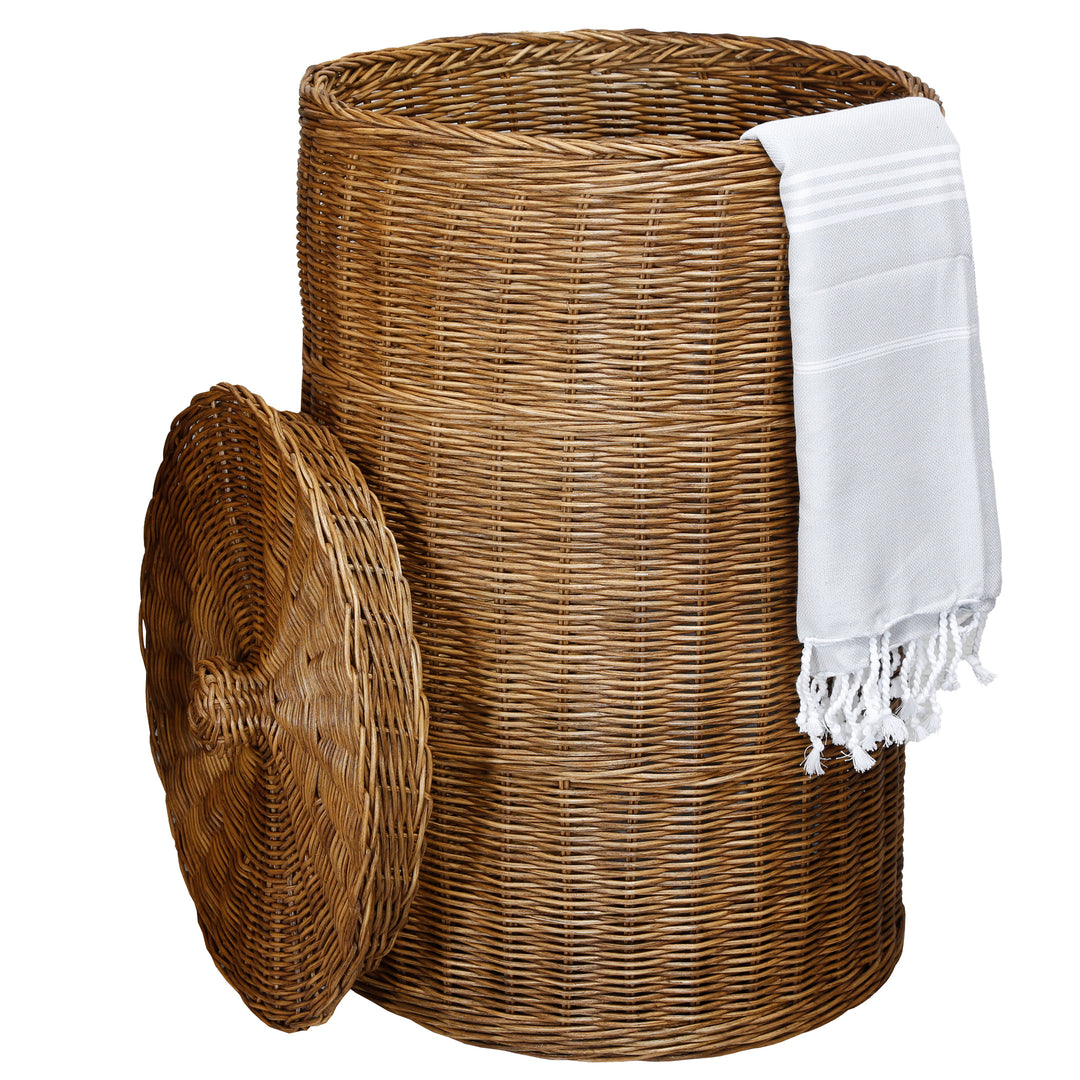 Dark, round laundry basket with a lid made of woven rattan, decorated with a white hammam towel