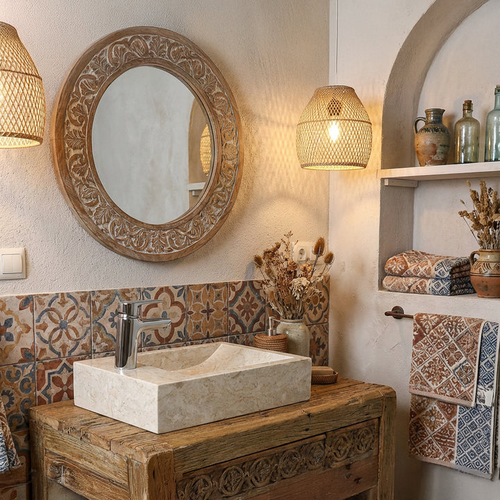 Rectangular countertop washbasin made of light natural stone on a wooden washstand in an oriental bathroom with patterned tiles and warm light