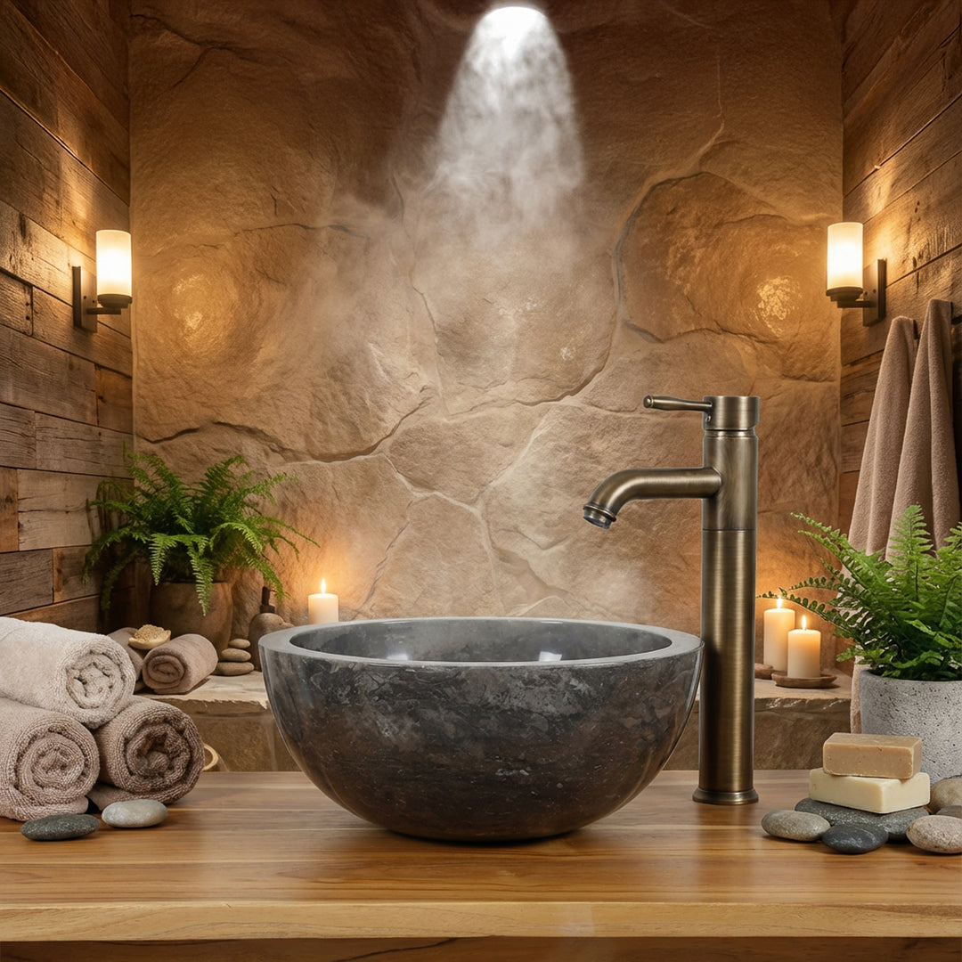 Round stone washbasin mounted on a wooden console with brass fittings in a warm spa bathroom ambience